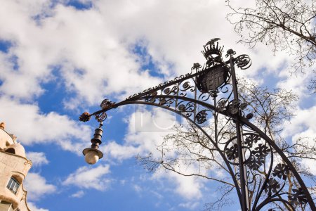 stylish artistic street lamp in barcelona against a blue sky with clouds