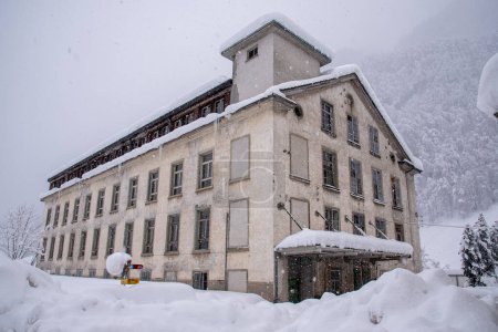 Téléchargez les photos : Ancienne usine textile abandonnée au milieu de la neige, à Diesbach, Glarus, Suisse - en image libre de droit