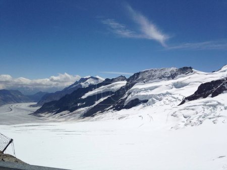 La imagen presenta una montaña nevada en Suiza, situada contra un cielo azul claro