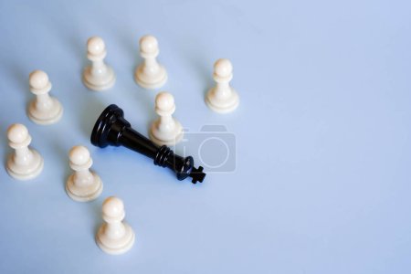 everal chess pawns surrounding a defeated chess king