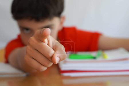 child, pre-teen doing homework with difficulties due to a mental health disorder, points to the camera, pointing out the special educational needs they require.