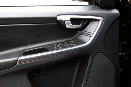Driver door trim. Window control buttons in modern SUV. Car leather interior details of door handle with windows controls and adjustments. Modern SUV leather Interior.