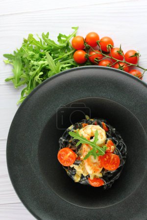 Foto de Espaguetis negros. Pasta de mariscos negros en plato blanco sobre fondo negro con espacio para copiar - Imagen libre de derechos