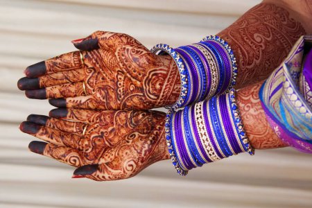 Une conception de henné nuptiale complimentant les beaux bracelets.