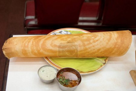 Foto de Crisp Elegance: Long Paper Dosa. Sirve junto a una variedad de chutneys vibrantes y sambar aromático, celebrando el rico patrimonio y la delicadeza culinaria de la cocina del sur de la India. - Imagen libre de derechos
