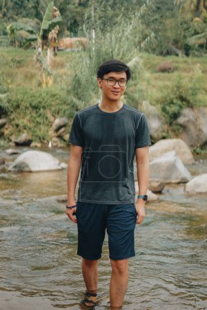 Photo for Asian Model, Adventurous Hiking Amid Sentul's Pine Forests, Crossing River, Embracing Nature's Beauty in Indonesia - Royalty Free Image