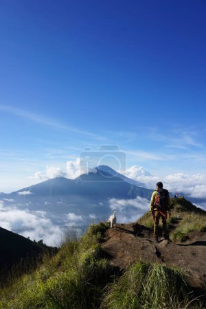 Photo for Asian Adventure, Man Model on Mountain Summit, Carrying Hiking Gear under Blue Sky above Ocean of Clouds - Royalty Free Image
