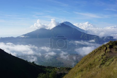 Photo for Above Cloud Nine, Mount Batur's Peak, Asian Man Trekker under Azure Sky and Cloud Sea - Royalty Free Image
