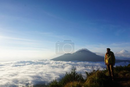 Asiatisches Abenteuer, Modell eines Mannes auf dem Berggipfel, Wanderausrüstung unter blauem Himmel über dem Ozean der Wolken