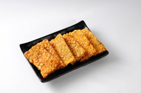 Photo for Fried tempeh served on a black plate, isolated white background, food traditional concept - Royalty Free Image