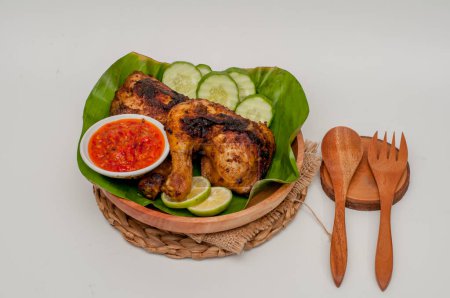 Photo for Grilled chicken with chili sauce on a wooden plate lined with banana leaves - Royalty Free Image