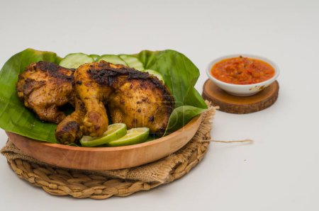 Photo for Grilled chicken with chili sauce on a wooden plate lined with banana leaves - Royalty Free Image