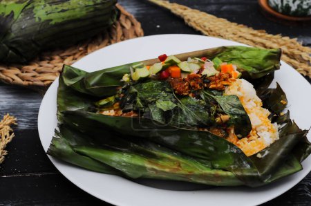 Téléchargez les photos : Nasi bakar (indonésien pour "riz brûlé ou grillé") désigne le riz cuit à la vapeur assaisonné avec des épices et des ingrédients et enveloppé dans une feuille de banane sécurisée avec du semat de lidi ( - en image libre de droit