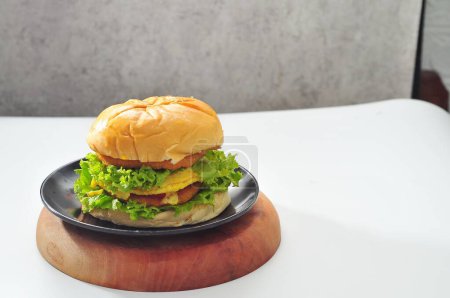 Téléchargez les photos : Hamburger rempli de légumes verts sur une assiette noire - en image libre de droit