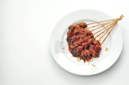 grilled meatballs on a plate of puti, spicy sauce and peanut sauce
