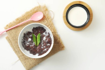 Black Glutinous Rice Porridge or Bubur Pulut Hitam in Malay with coconut milk on white background
