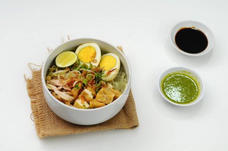 Soto vient de la nourriture chinoise dans le dialecte Hokkian Cau do, Jao To, ou Chau Tu, qui signifie "herbe" ou "abats d'épices". servi sur un bol blanc avec tofu, poulet et ?uf bouilli