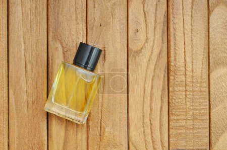 Foto de La mano de un hombre sostiene una botella de perfume sobre una mesa de madera - Imagen libre de derechos