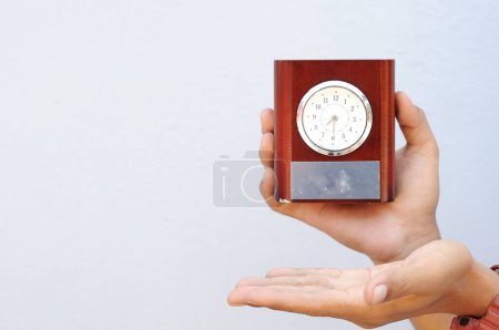 Téléchargez les photos : La main d'un homme tenant une horloge pour une table d'étude - en image libre de droit