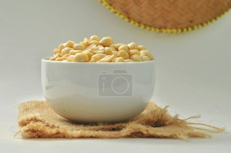 Téléchargez les photos : Cacahuète crue dans un bol blanc sur un fond blanc isolé - en image libre de droit