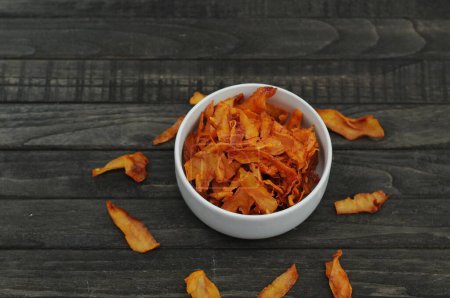 cassava chips with spicy taste in a white bowl on black wood table