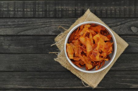 Photo for Cassava chips with spicy taste in a white bowl on black wood table - Royalty Free Image