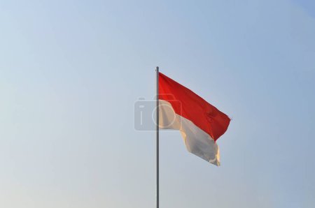 Téléchargez les photos : Drapeau indonésien sur le mât du drapeau dans le ciel bleu. - en image libre de droit