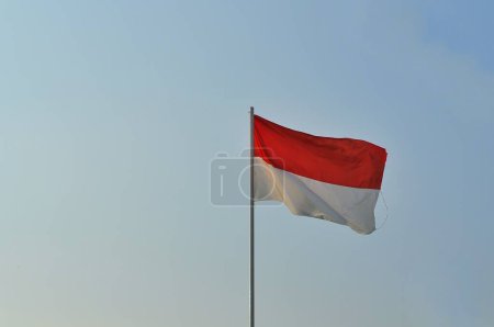 Téléchargez les photos : Drapeau d'indonésie agitant sur le vent contre un ciel bleu - en image libre de droit