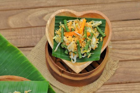Photo for Selective focus Urap Sayur is Indonesian traditional food. a salad dish of steamed various vegetables mixed with seasoned and spiced, served on banana leaf and wood plate - Royalty Free Image