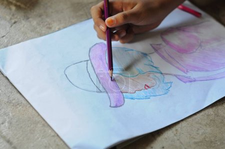  Les mains d'un enfant colorient son travail