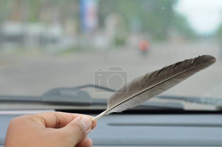 Téléchargez les photos : Main avec plume avec fond bokeh - en image libre de droit