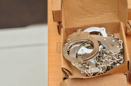 Téléchargez les photos : Menottes de chaîne dans une boîte en carton - en image libre de droit