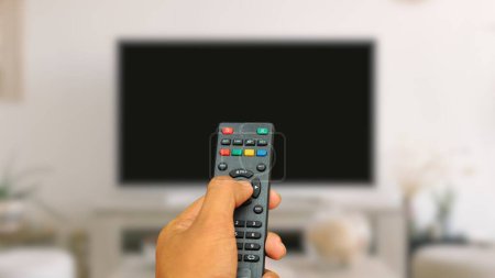 Foto de Una mano del hombre mantenga la TV a distancia con luz de fondo bokeh - Imagen libre de derechos