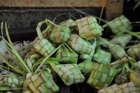Photo for Ketupat (in Indonesian and Malay), or kupat (in Javanese and Sundanese), or tipat (in Balinese) is a Javanese rice cake packed inside a diamond-shaped container of woven palm leaf pouch, - Royalty Free Image