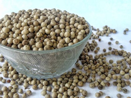 Pure white pepper, a crushed spice with a pungent, spicy aroma, is stacked in a glass bowl