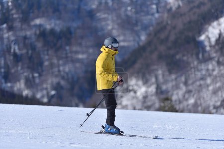 Téléchargez les photos : Une journée parfaite pour le ski - L'homme aventureux affronte les pistes lors d'une journée Bluebird avec le paysage montagneux magnifique comme compagnon - en image libre de droit