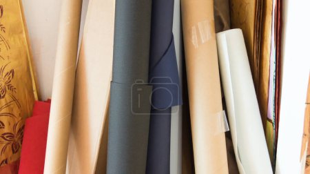 Photo for Some rolls of canvas unfinished and still on the roll, dark blue, white and beige in the background still other art supplies - Royalty Free Image