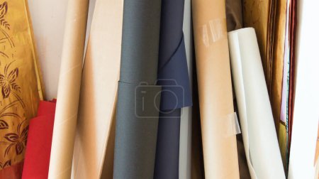 Photo for Some rolls of canvas unfinished and still on the roll, dark blue, white and beige in the background still other art supplies - Royalty Free Image