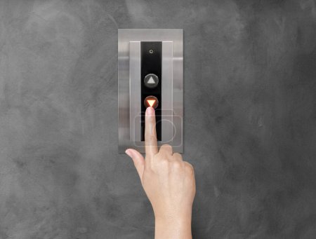 A woman's hand is using her finger to press the elevator button.