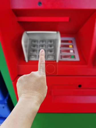 Die Hand eines Mannes, der kurz davor ist, Code auf der Zahlentastatur des Geldautomaten einzugeben, verschwommen.
