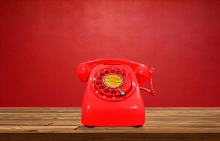 Foto de Teléfono vintage rojo sobre mesa de madera con fondo rojo - Imagen libre de derechos
