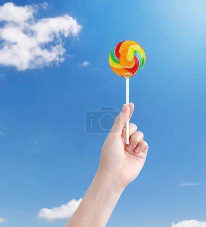 Lollipop candy on hand on bright sky background  summer concept