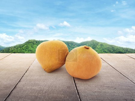 A santol ripened on a wooden table with a background of mountain