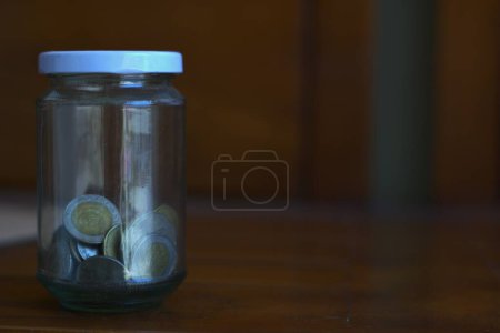Illustration of savings and finances with copy space for text, a jar containing rare Indonesian rupiah coin