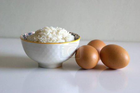 A bowl of rice and eggs on the table, cooking ingredient