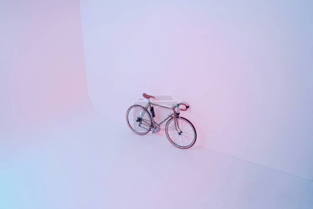 A bicycle is on a white background with a pink and blue background.