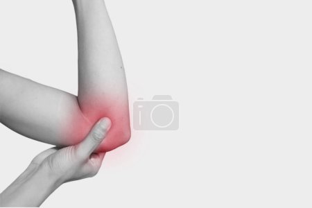 Woman has acute pain in the elbow. The young woman holds on an elbow. Black and white photo and red spot.With copy space for text or anything for Your healty company. health concept. 