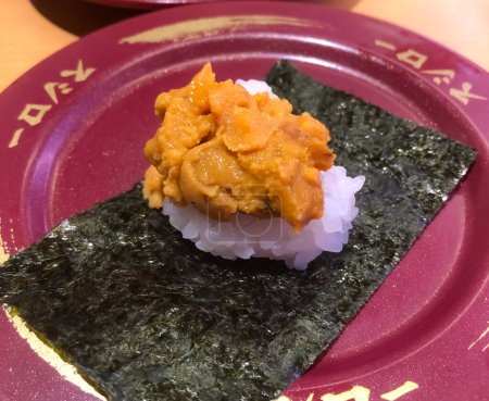 Foto de Tokio, Japón - 19 de enero de 2024: vista cercana del sushi uni en un plato granate, comida típica japonesa en un restaurante de sushi llamado sushiro - Imagen libre de derechos