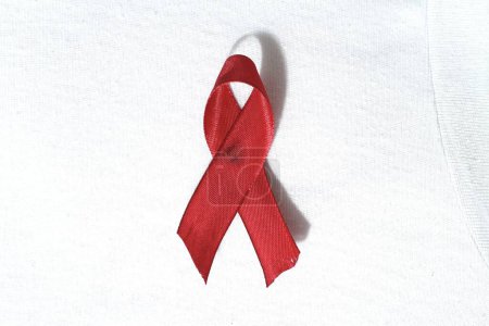 Ruban rouge sur pantalon en denim, symbole de prévention de la toxicomanie, solidarité des personnes vivant avec le VIH luttant contre le sida. Journée mondiale du sida. Concept de promotion du bilan de santé.