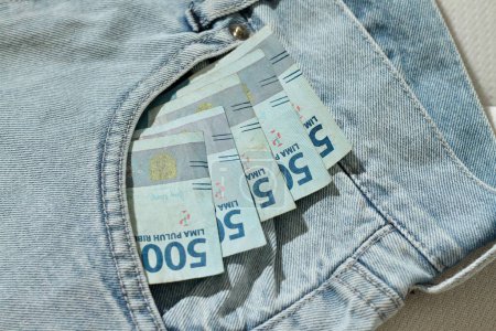 Photo for Putting money in the pocket of blue jeans, rupiah money or indonesia money in the jeans pocket.finance concept.IDR 50,000 - Royalty Free Image